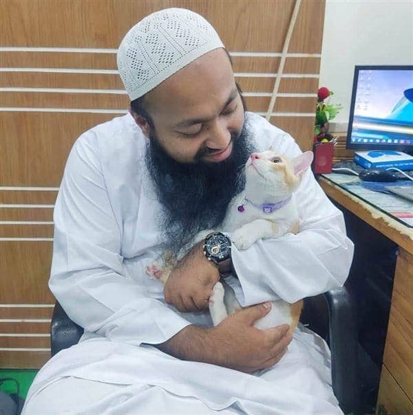 Dr Saddam Hossain at the clinic, holding a white and ginger cat